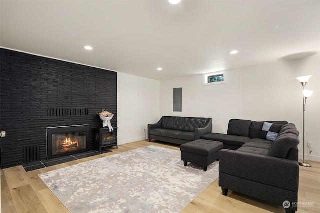 living room featuring a fireplace, electric panel, and light wood-type flooring