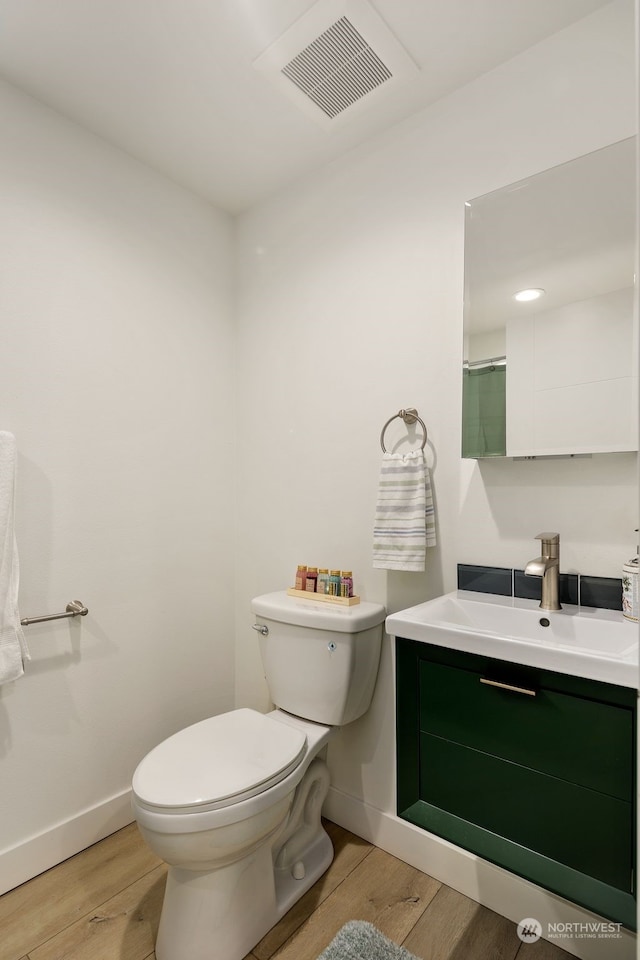 bathroom featuring toilet, vanity, and hardwood / wood-style flooring