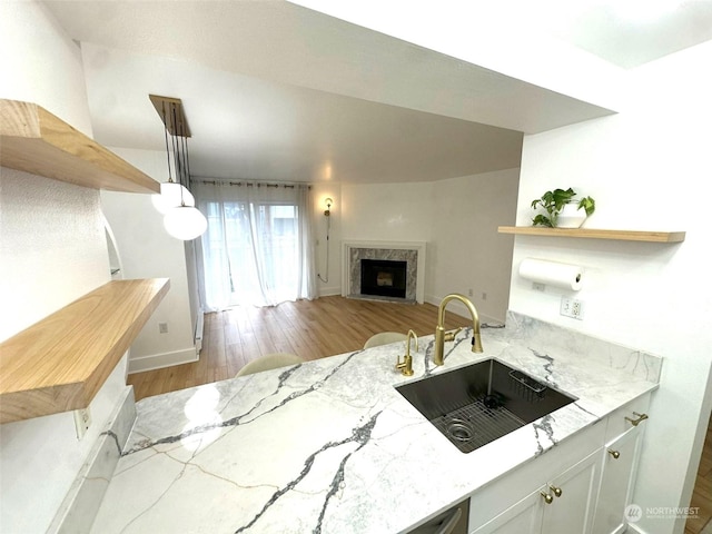 kitchen featuring decorative light fixtures, a high end fireplace, light stone countertops, and sink