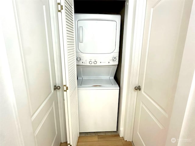 laundry room with stacked washer and clothes dryer and light hardwood / wood-style floors