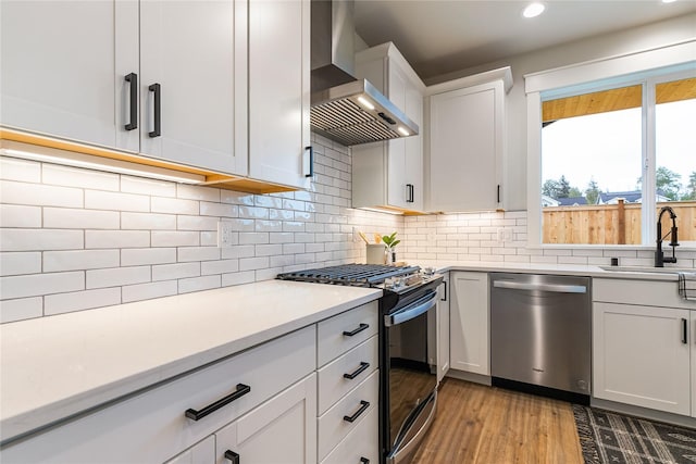 5986 Ranch Loop, Ferndale, WA 98248 - kitchen featuring dishwasher, black gas range oven, a sink, wall chimney range hood, and light wood finished floors