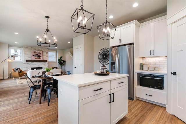 5986 Ranch Loop, Ferndale, WA 98248 - kitchen with black microwave, a chandelier, stainless steel fridge with ice dispenser, light wood-style flooring, and a fireplace