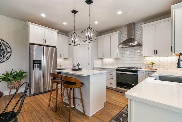 5986 Ranch Loop, Ferndale, WA 98248 - kitchen featuring stainless steel appliances, wall chimney range hood, a sink, a center island, and a kitchen bar