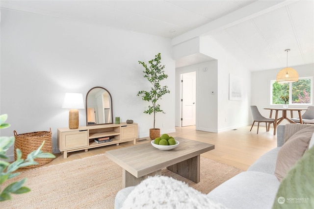 living room featuring light wood-type flooring and vaulted ceiling with beams