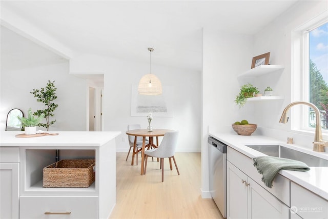 kitchen with decorative light fixtures, light wood-type flooring, dishwasher, white cabinets, and sink