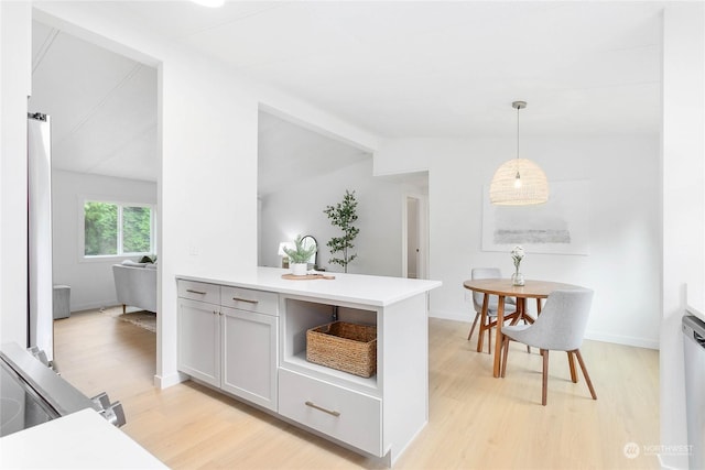 kitchen with pendant lighting, vaulted ceiling, kitchen peninsula, and light wood-type flooring