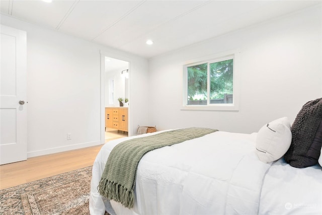 bedroom with hardwood / wood-style floors and ensuite bath