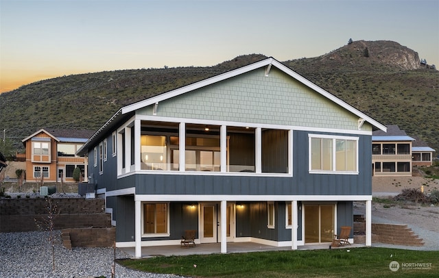 back of house at dusk with a patio area and a mountain view