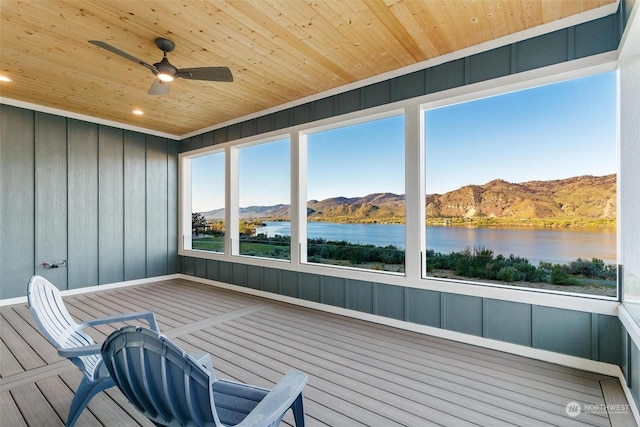 unfurnished sunroom with wood ceiling, ceiling fan, and a water and mountain view