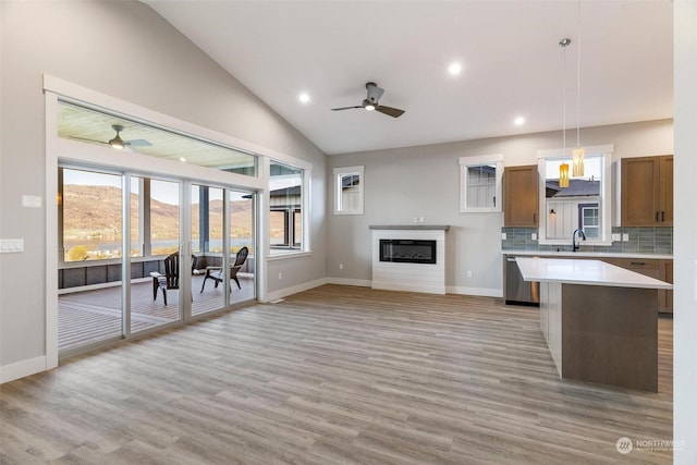 kitchen featuring a sink, open floor plan, light countertops, a center island, and pendant lighting