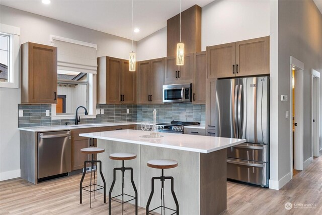 kitchen with a sink, a kitchen breakfast bar, light countertops, appliances with stainless steel finishes, and a center island