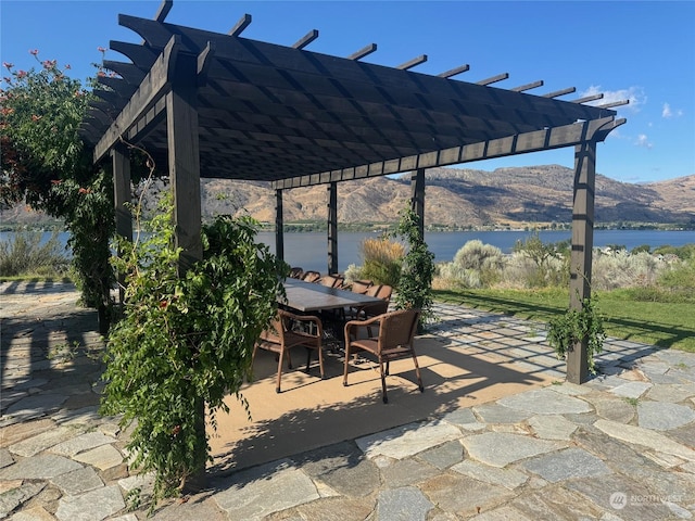 view of patio / terrace with a water and mountain view, outdoor dining area, and a pergola