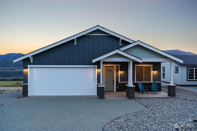 view of front facade with a garage, covered porch, driveway, and board and batten siding