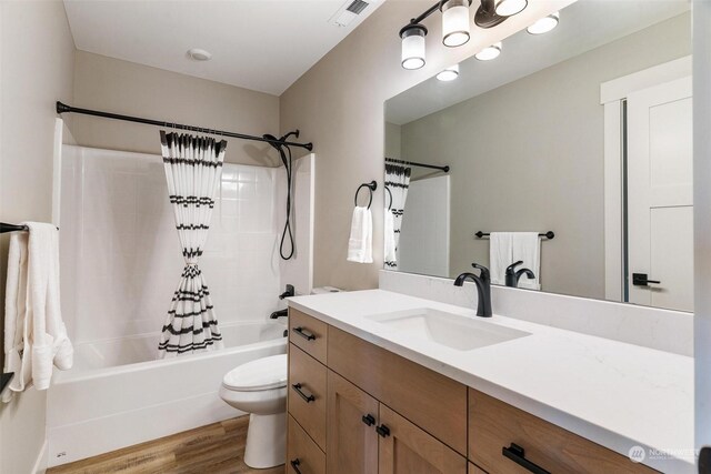 bathroom featuring toilet, wood finished floors, vanity, visible vents, and shower / tub combo with curtain