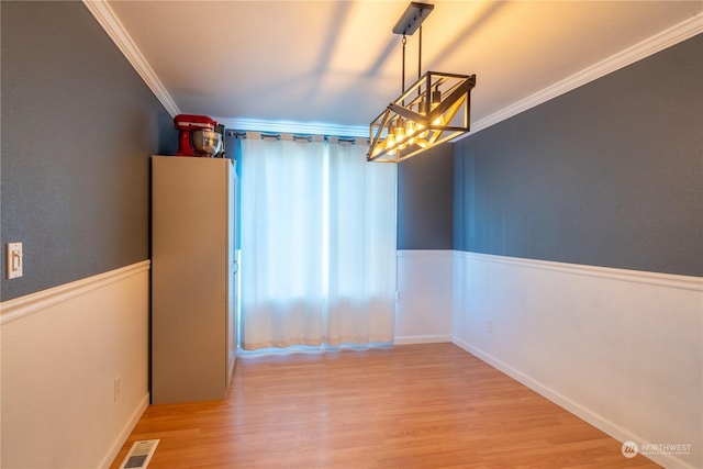 unfurnished dining area featuring light hardwood / wood-style floors and crown molding