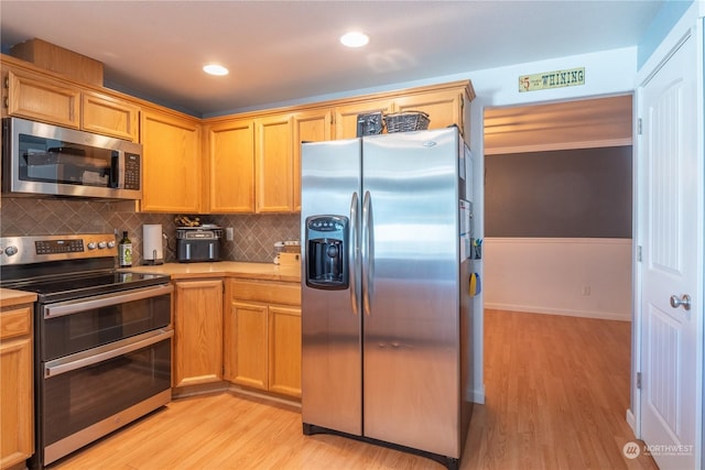 kitchen with backsplash, stainless steel appliances, and light wood-type flooring