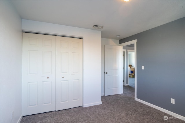 unfurnished bedroom featuring dark carpet and a closet