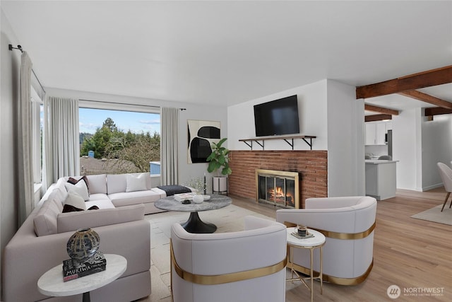 living room with beam ceiling, a brick fireplace, and light wood-type flooring