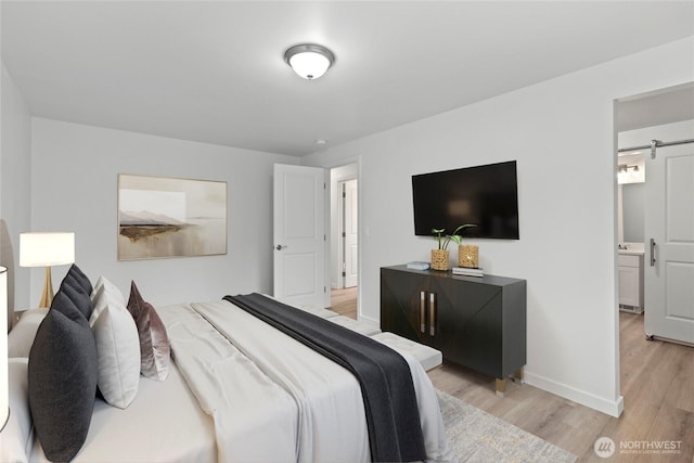 bedroom featuring a barn door, baseboards, and light wood-style floors