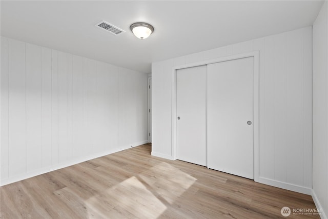 unfurnished bedroom with a closet, visible vents, and wood finished floors