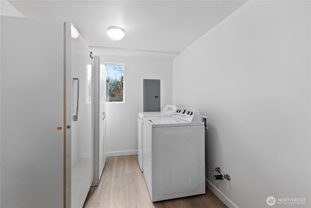 washroom featuring baseboards, electric panel, laundry area, light wood-style floors, and washer and dryer