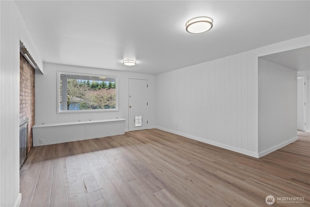 unfurnished room featuring a fireplace, baseboards, and wood finished floors