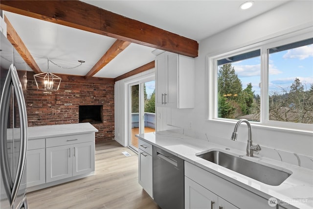 kitchen featuring light stone counters, beamed ceiling, stainless steel appliances, and a sink