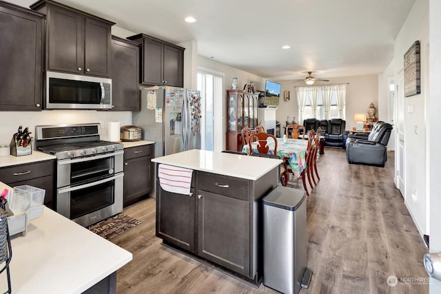 kitchen with dark brown cabinets, appliances with stainless steel finishes, a wealth of natural light, and a center island