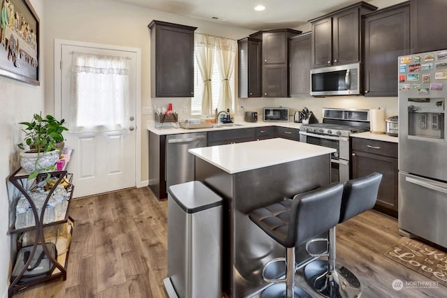 kitchen featuring a center island, a breakfast bar, dark hardwood / wood-style flooring, appliances with stainless steel finishes, and dark brown cabinets