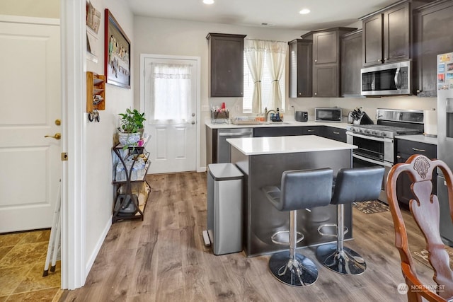 kitchen featuring dark brown cabinetry, a breakfast bar, appliances with stainless steel finishes, and a kitchen island