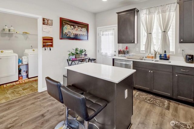 kitchen with dishwasher, washer and dryer, a center island, sink, and light wood-type flooring