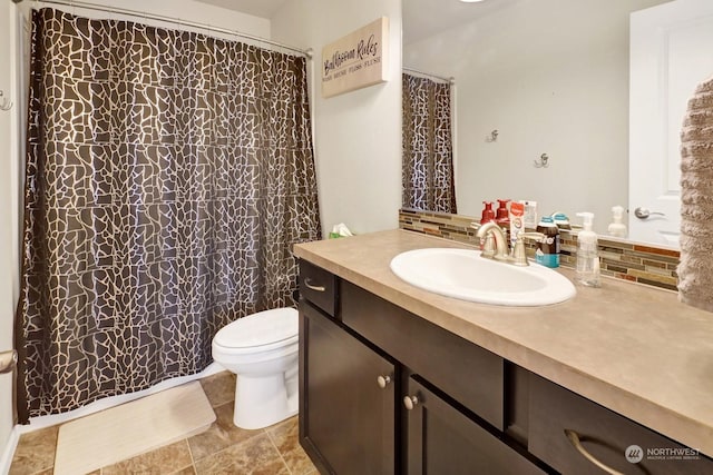 bathroom featuring toilet, decorative backsplash, and vanity