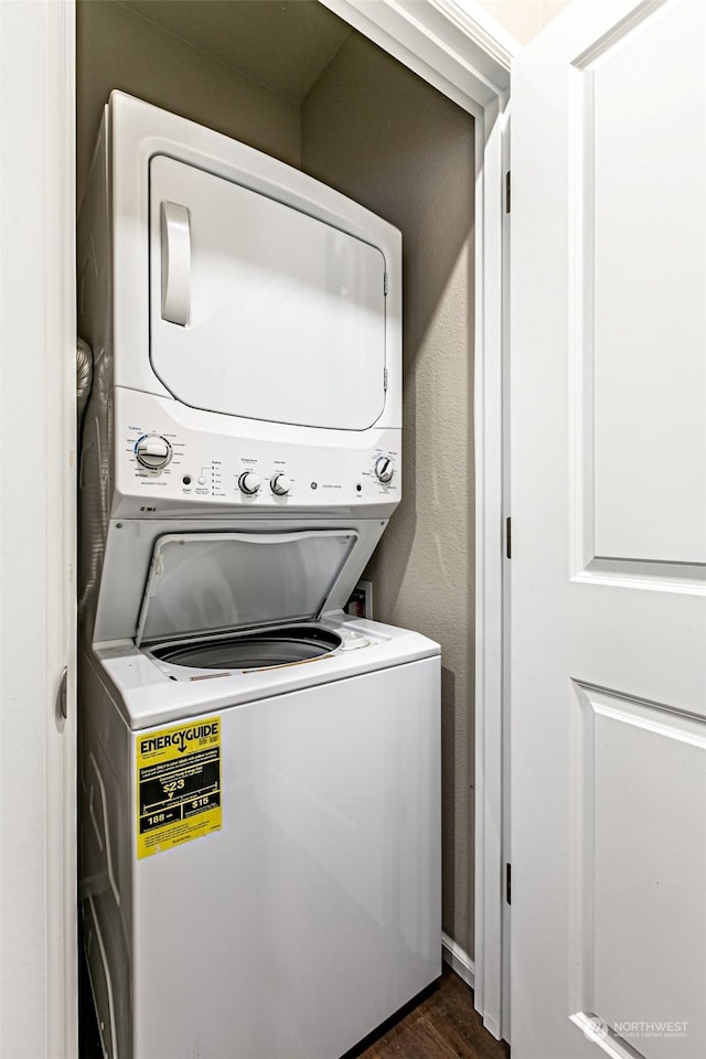 laundry room featuring dark hardwood / wood-style floors and stacked washer and dryer