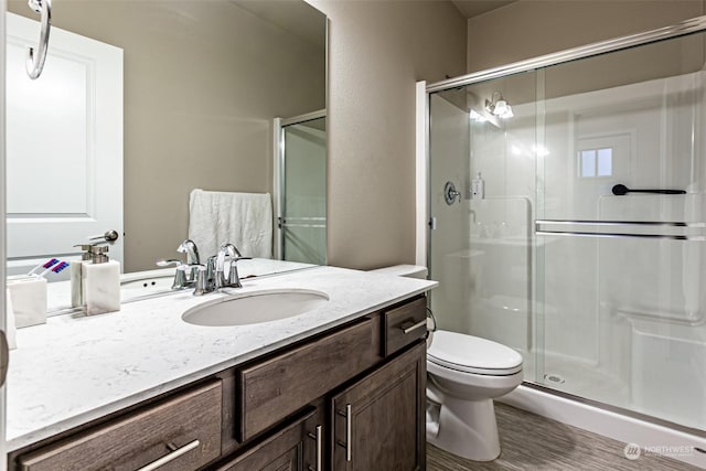 bathroom featuring vanity, toilet, and a shower with door