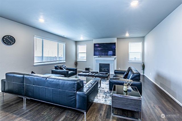 living room featuring dark wood-type flooring, a wealth of natural light, and a tiled fireplace