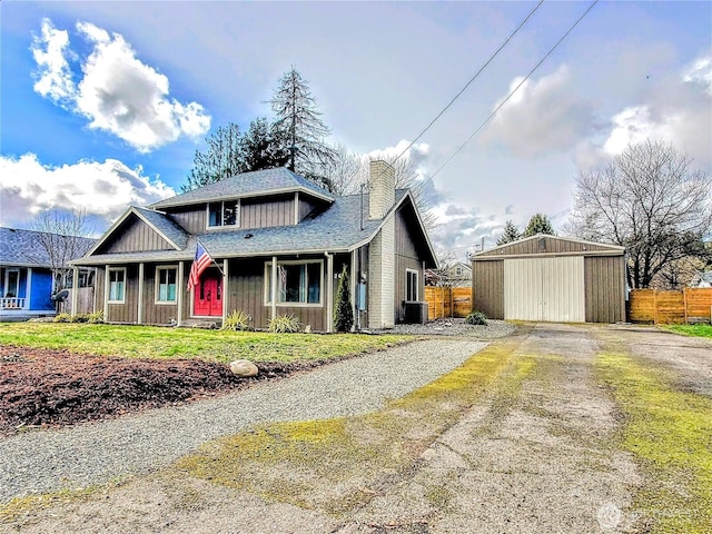 view of front of home with an outbuilding, a chimney, driveway, and fence