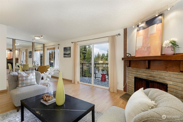 living room with track lighting, a textured ceiling, light hardwood / wood-style floors, and a fireplace