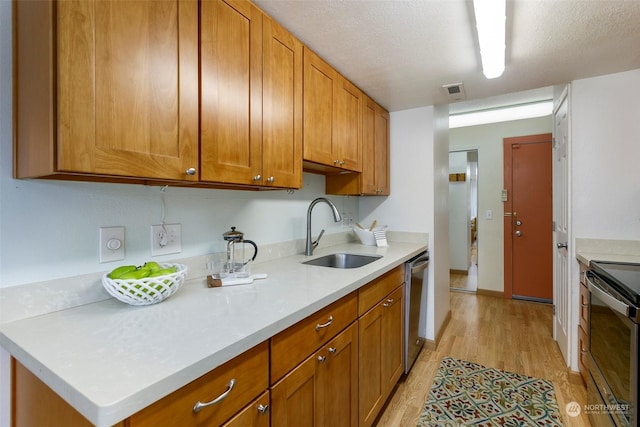 kitchen with a textured ceiling, dishwasher, sink, electric range, and light hardwood / wood-style flooring