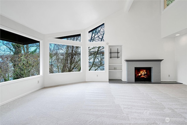 unfurnished living room with high vaulted ceiling, a fireplace, and light carpet