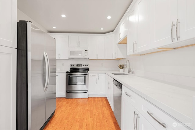 kitchen featuring sink, light wood-type flooring, white cabinetry, and stainless steel appliances