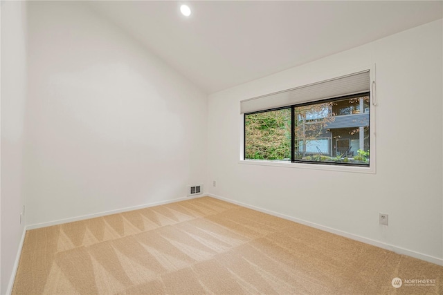 carpeted empty room featuring vaulted ceiling