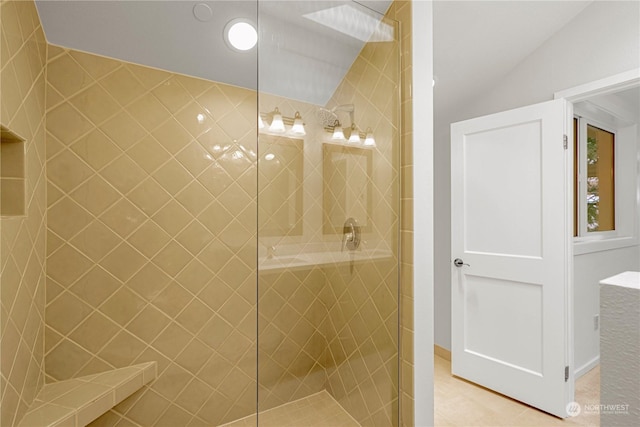 bathroom with vaulted ceiling, a tile shower, and tile patterned flooring