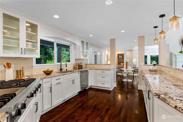 kitchen with hanging light fixtures, sink, white cabinets, stainless steel appliances, and dark hardwood / wood-style floors