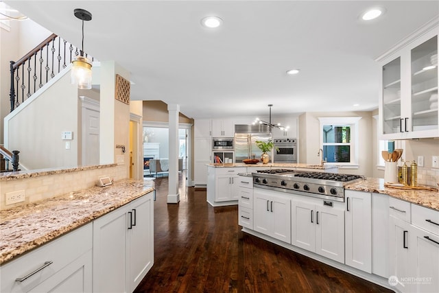 kitchen with hanging light fixtures, white cabinetry, dark hardwood / wood-style floors, decorative backsplash, and built in appliances