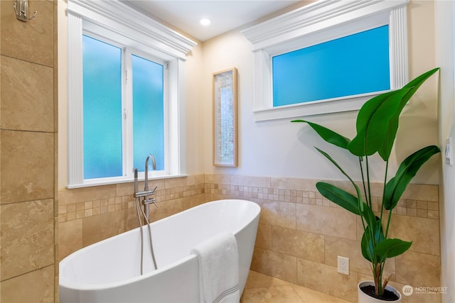 bathroom featuring a washtub, tile patterned floors, and tile walls