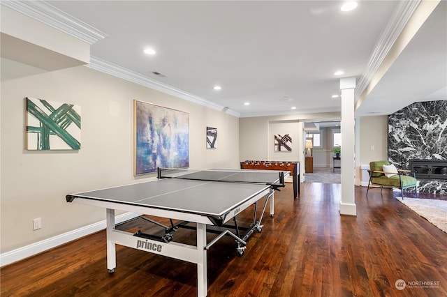 rec room featuring dark wood-type flooring, crown molding, and ornate columns