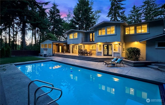 pool at dusk featuring a patio area