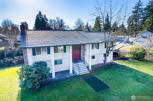 raised ranch featuring a chimney and a front lawn