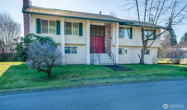 split foyer home featuring entry steps, a chimney, and a front lawn