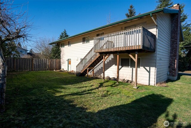 rear view of house featuring fence, a wooden deck, a yard, a chimney, and stairs